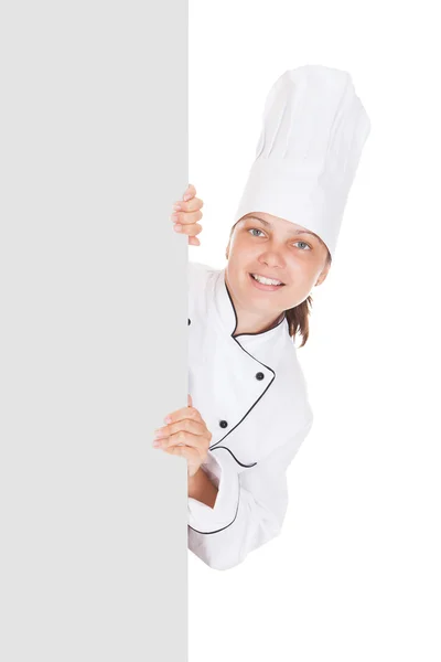 Chef fêmea apontando no cartaz em branco — Fotografia de Stock