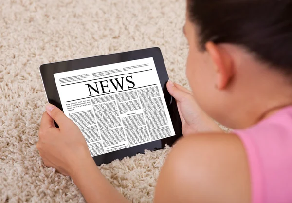 Mujer joven leyendo un artículo de noticias sobre la tableta digital —  Fotos de Stock