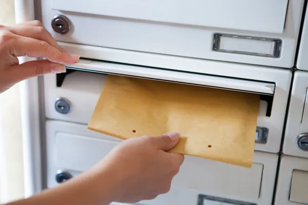 Femme mettant l'enveloppe dans la boîte aux lettres — Photo