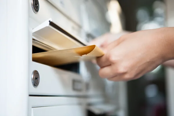 Frau steckt Umschlag in Briefkasten — Stockfoto