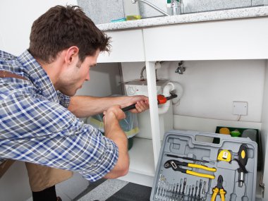 Plumber Fixing Sink In Kitchen clipart