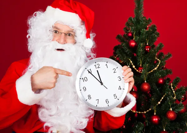 Porträt eines glücklichen Weihnachtsmannes, der die Uhr hält — Stockfoto