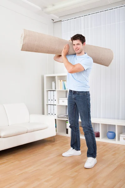 Jovem homem segurando tapete — Fotografia de Stock