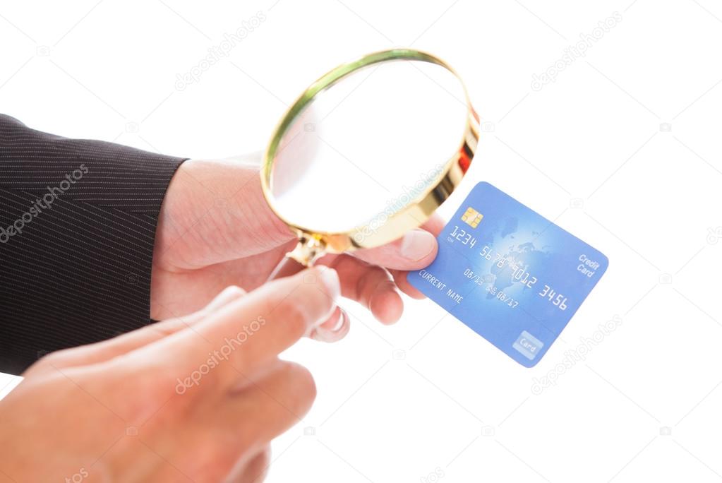 Man Holding Credit Card And Magnifying Glass