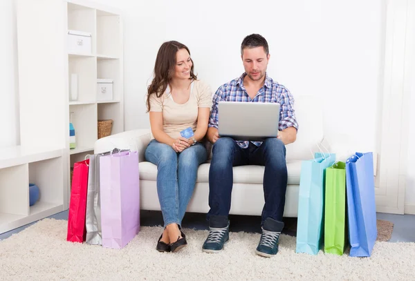 Casal jovem sentado no sofá Compras Online — Fotografia de Stock