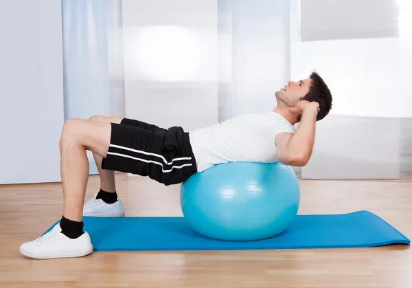 Homem fazendo sentar-se Ups na bola de fitness — Fotografia de Stock