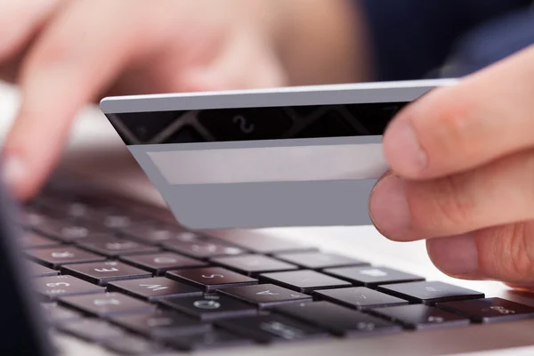Persona que sostiene la tarjeta de crédito usando el ordenador portátil —  Fotos de Stock