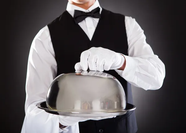 Мужчина официант держит поднос и крышку — стоковое фото