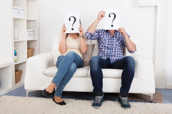 Paar hält Fragezeichen vor Gesicht — Stockfoto