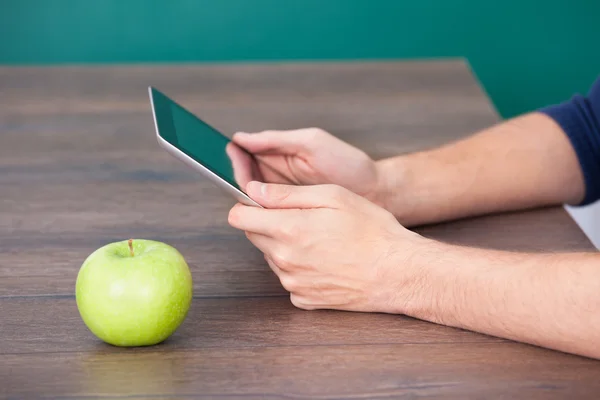 Person Using Digital Tablet Besides Green Apple — Stock Photo, Image