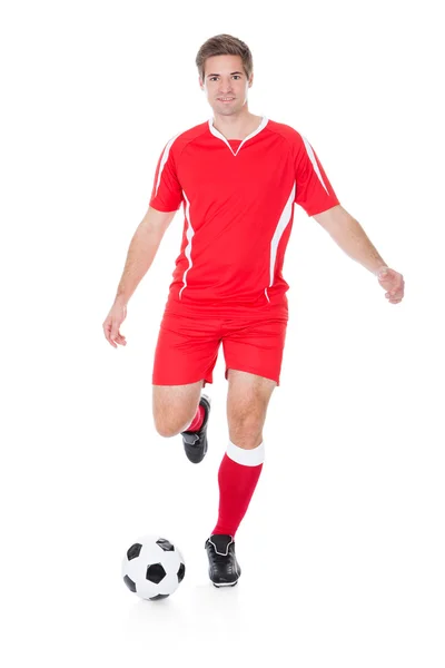 Jogador de futebol chutando futebol — Fotografia de Stock