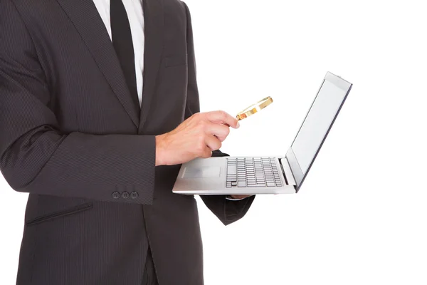 Чоловік тримає ноутбук і збільшувальним склом — стокове фото