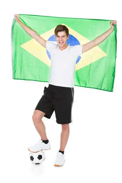 Jogador de futebol segurando a bandeira do Brasil — Fotografia de Stock