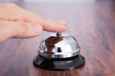 Hand Ringing Service Bell Kept On Wooden Table clipart