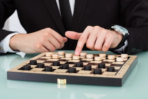 Бизнесмен играет в шашки — стоковое фото