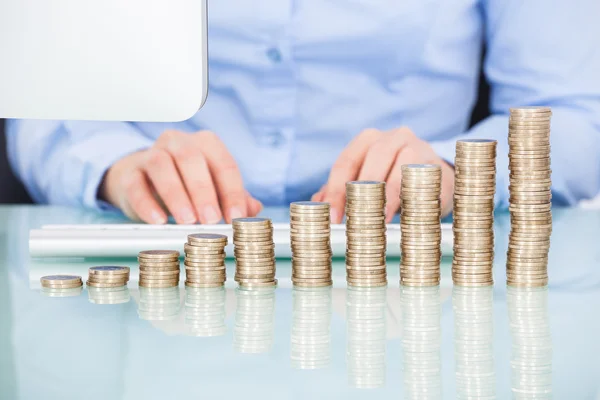 Monedas apiladas en el escritorio delante de la mujer de negocios —  Fotos de Stock