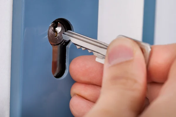 Mão colocando a chave da casa na porta — Fotografia de Stock