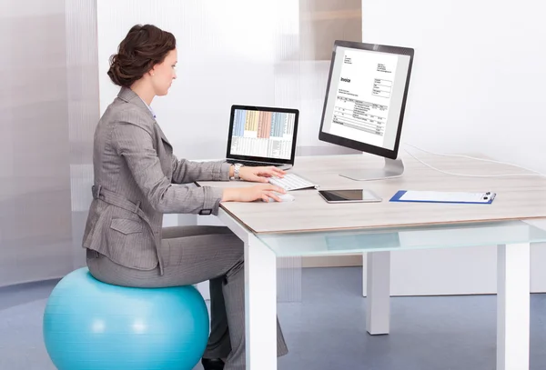 Kvinna sitter på pilates boll med hjälp av dator — Stockfoto