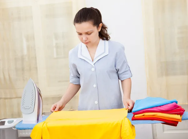 Jonge vrouw strijken kleding — Stockfoto