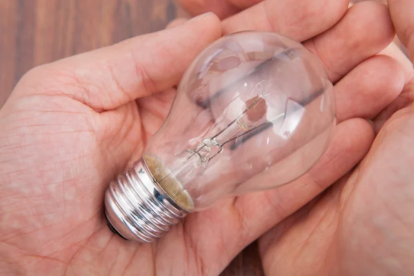 Mano della persona sulla lampada da tavolo in legno — Foto Stock