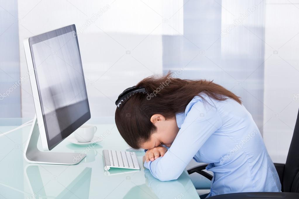Tired Businesswoman Leaning At Office Desk