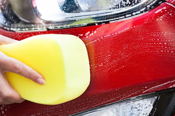 Lavado a mano coche rojo con esponja amarilla — Foto de Stock
