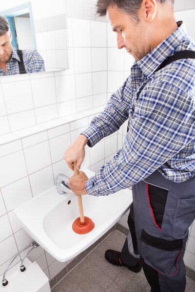 Plumber Pressing Plunger In Sink