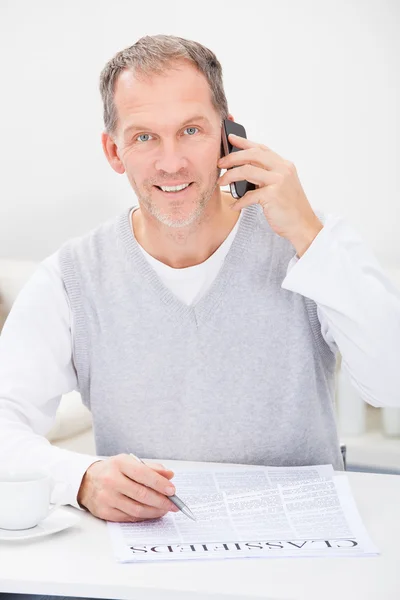 Mannen framför tidningen talar i mobiltelefon — Stockfoto