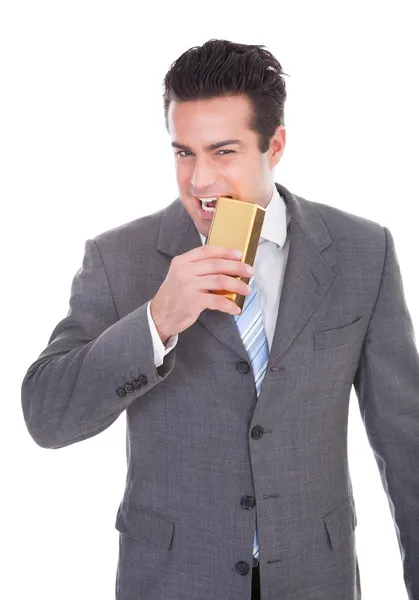 Empresário mordendo barra de ouro — Fotografia de Stock