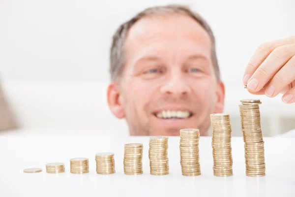 Hombre maduro apilando monedas — Foto de Stock