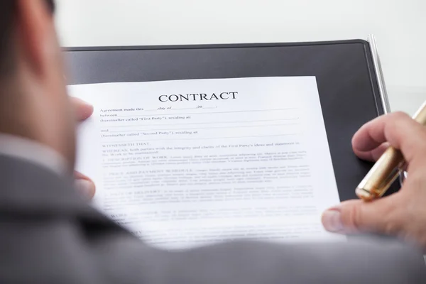 Person Looking At Contract Form Holding Pen