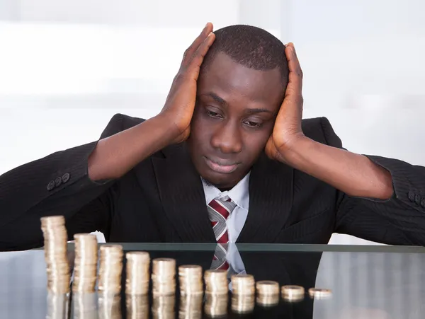 Besorgter Geschäftsmann schaut auf Münzen — Stockfoto