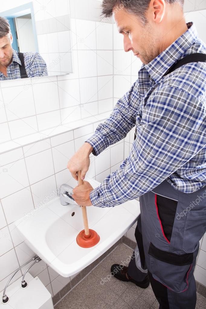 Plumber Pressing Plunger In Sink