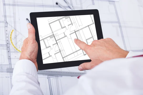 Manliga arkitekt analysera blueprint över digital tablet — Stockfoto