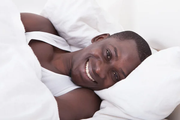 Africký muž ležící na posteli — Stock fotografie