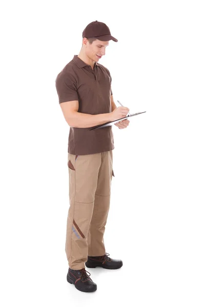 Joven repartidor escribiendo en portapapeles — Foto de Stock