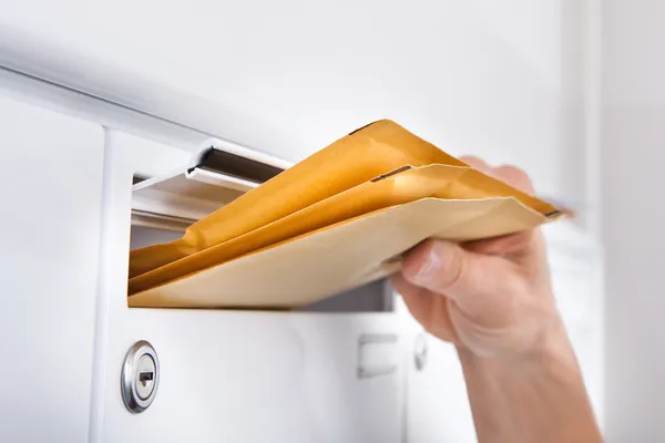 Postman вставляє літери в поштову скриньку — стокове фото