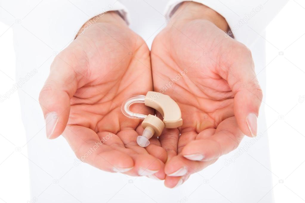 Person Holding Hearing Aid In Cupped Hands