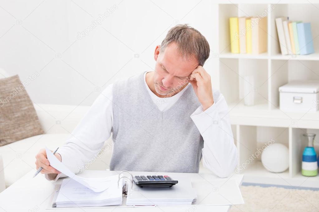 Thoughtful Man Holding Calculator