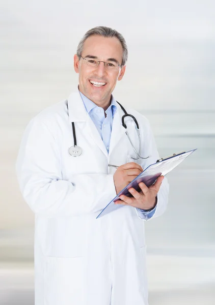 Médico feliz escrevendo na área de transferência — Fotografia de Stock