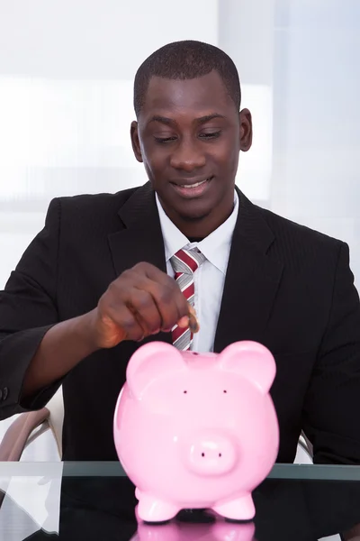 ビジネスマン piggybank でコインを挿入します。 — ストック写真