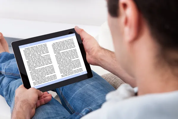 Homme tenant un dispositif d'écran tactile montrant un livre électronique — Photo