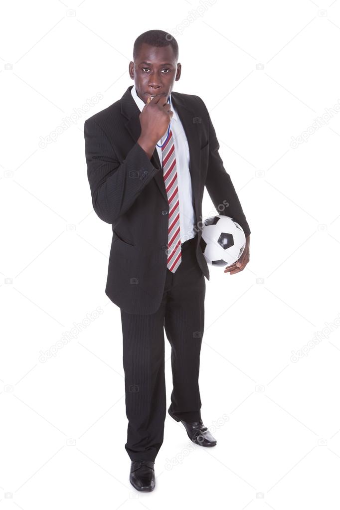 Businessman Blowing Whistle Holding Football