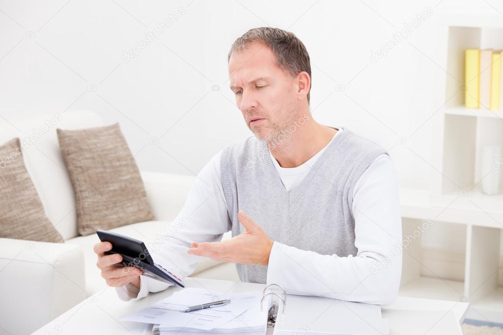 Thoughtful Man Holding Calculator