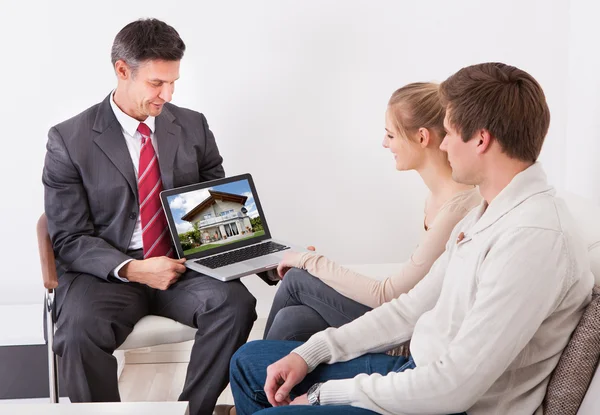 Агент по недвижимости показывает ноутбук паре — стоковое фото