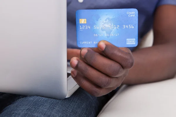 Mano con ordenador portátil y tarjeta de crédito — Foto de Stock