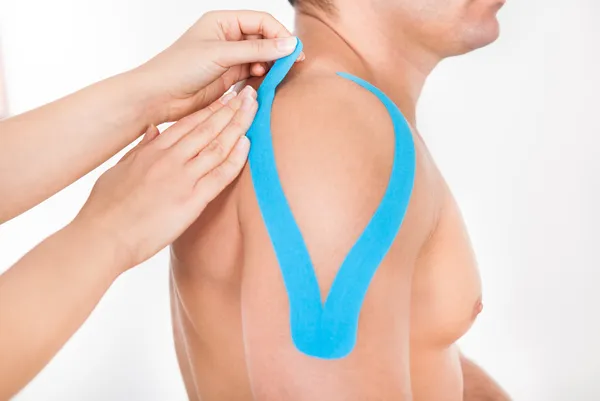 Person klebt Physio-Tape an Mann — Stockfoto