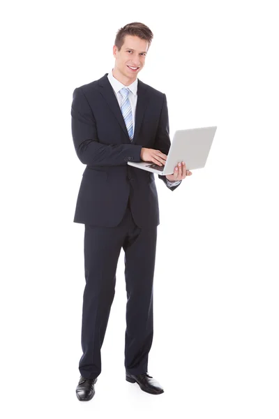 Jeune homme d'affaires tenant un ordinateur portable Image En Vente