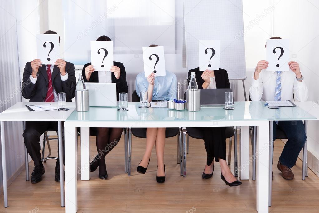 Businesspeople Holding Question Mark In Front Of Face