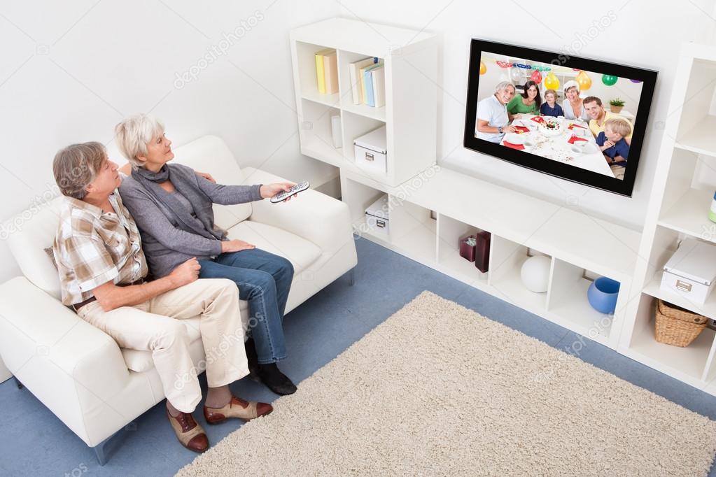 Senior Couple Changing Channel Of Television